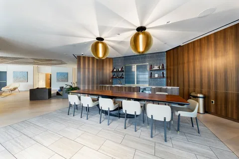 a dining hall with couches a dining table and chairs with wooden floor