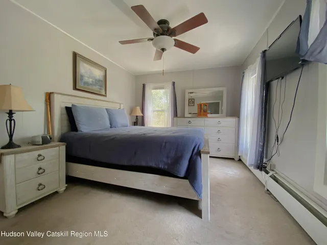 a spacious bedroom with a bed a couch and a flat tv screen on dresser