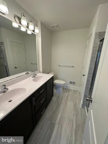 a bathroom with a sink a toilet a mirror and shower