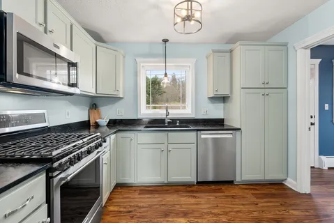 a kitchen with stainless steel appliances granite countertop a stove a sink and a microwave
