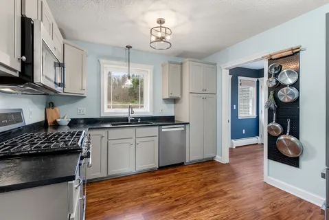 a kitchen with stainless steel appliances granite countertop a sink cabinets and wooden floor