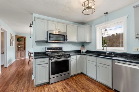 a kitchen with stainless steel appliances granite countertop a stove a sink and a microwave
