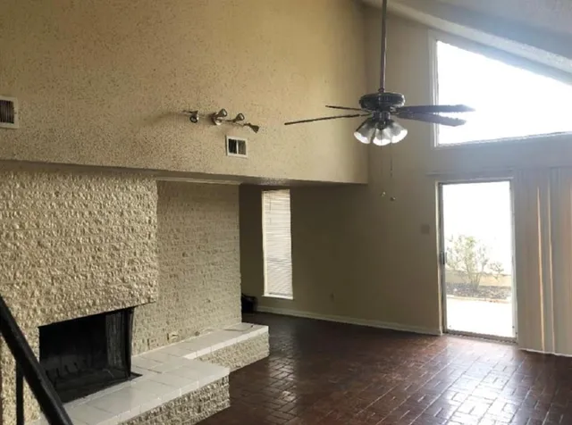 an empty room with wooden floor fireplace and windows