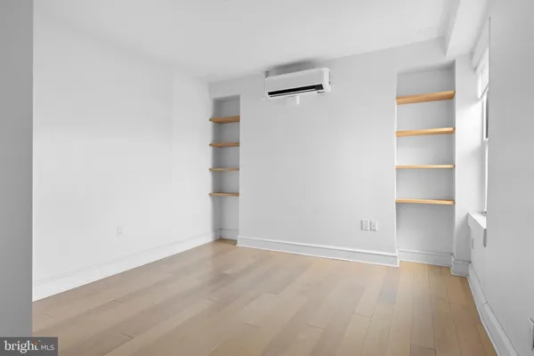 a view of an empty room with wooden floor and closet