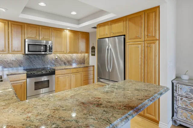 a kitchen with stainless steel appliances granite countertop a refrigerator a stove a sink and a microwave