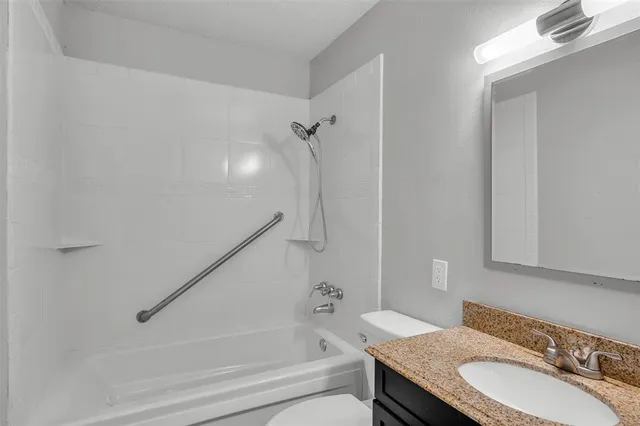 a bathroom with a granite countertop sink a toilet and shower