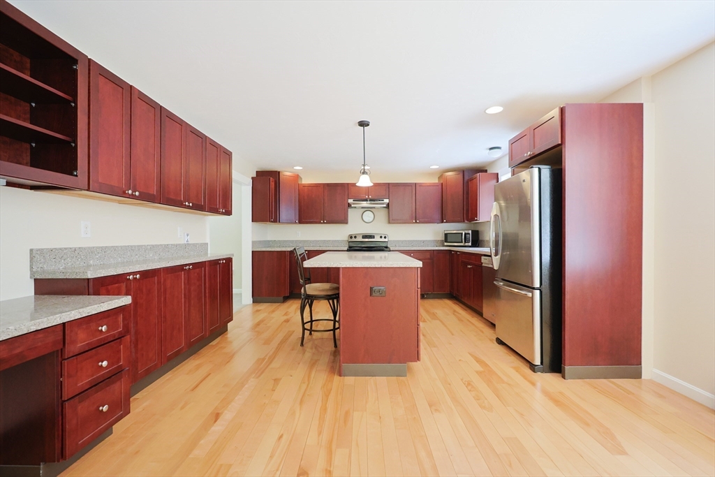 68 Dresser Hill Road, Unit 2 Dudley, MA 01571 - Photo 8 of 39 a kitchen with stainless steel appliances granite countertop a refrigerator a stove top oven a sink dishwasher and wooden cabinets with wooden floor