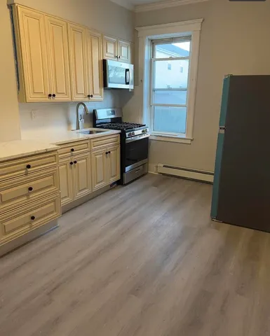 a kitchen with granite countertop a refrigerator a sink and dishwasher a stove with wooden floor