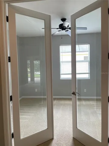 a view of an empty room with a chandelier fan and a window
