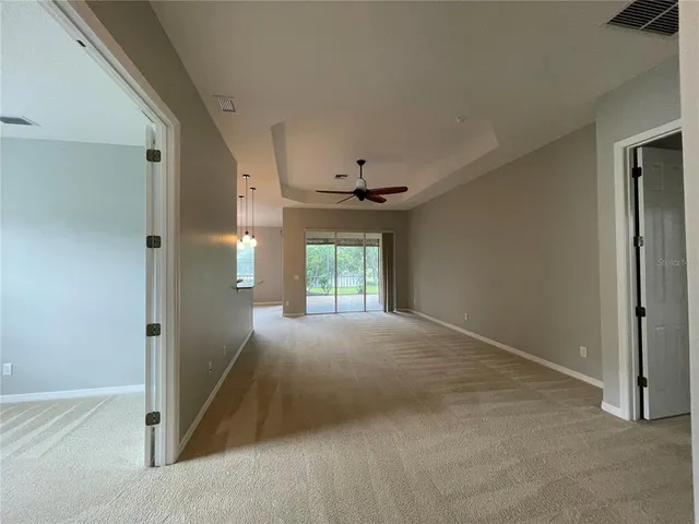 a view of an empty room with window and chandelier