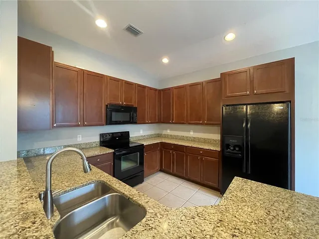 a backyard of a house with table and chairs plants and large tree
