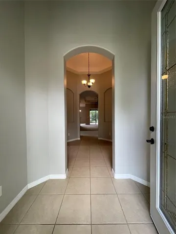 a view of a hallway with wooden floor and a chandelier