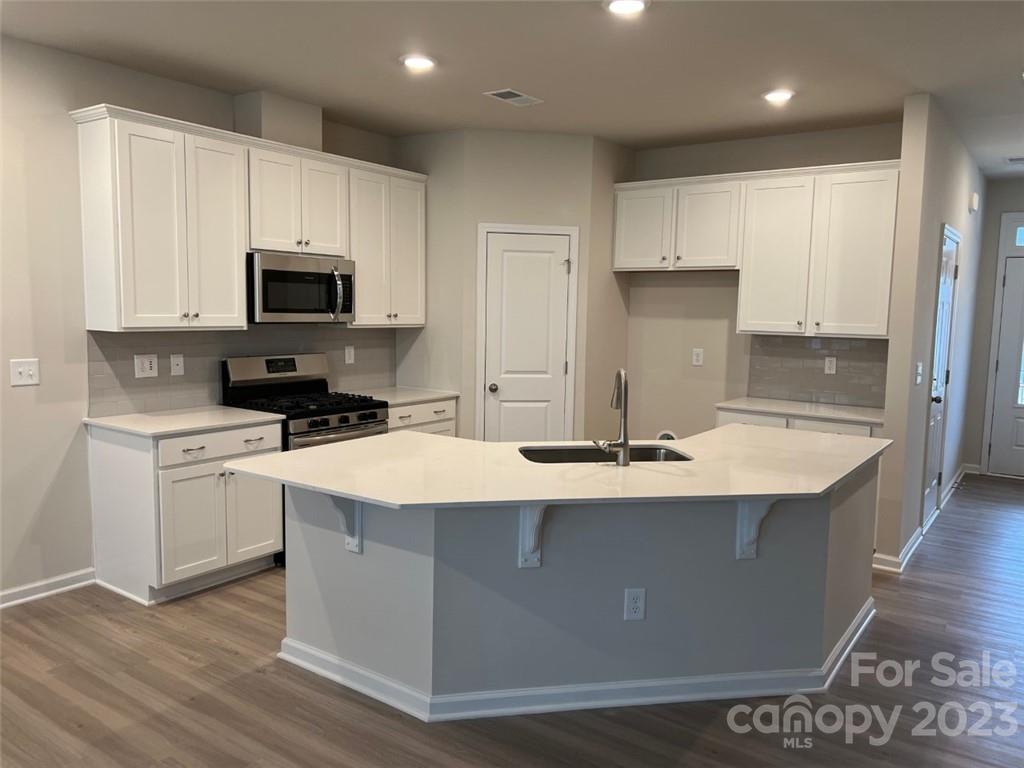 6021 Chelsea Oaks Ridge, Unit 2084 Tega Cay, SC 29708 - Photo 11 of 12 a kitchen with kitchen island white cabinets appliances and sink