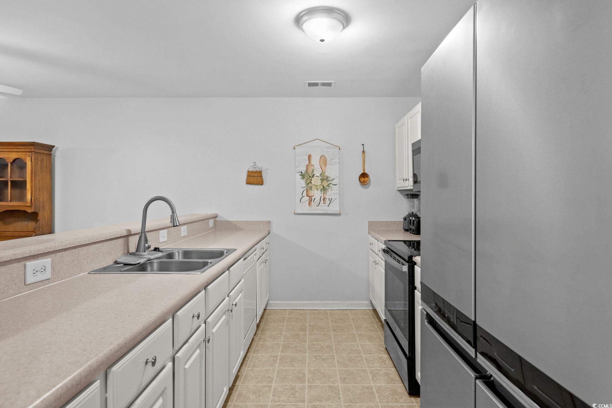 4849 Meadowsweet Drive, Unit 1606 Myrtle Beach, SC 29579 - Photo 11 of 36 Kitchen with stainless steel appliances, light countertops, white cabinets, and a peninsula