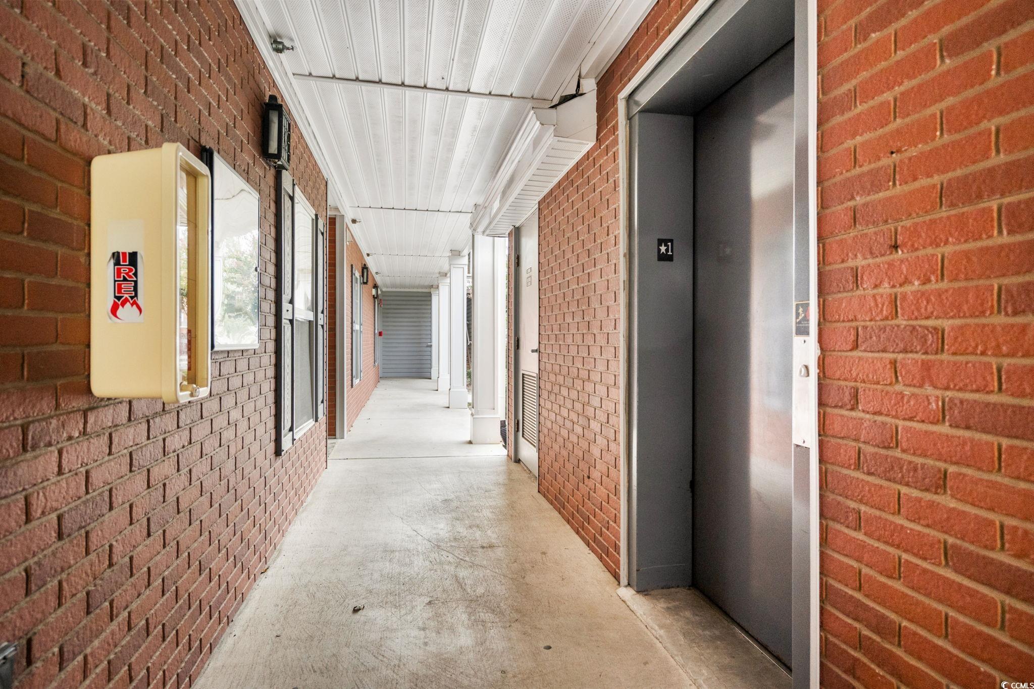 4849 Meadowsweet Drive, Unit 1606 Myrtle Beach, SC 29579 - Photo 26 of 36 Corridor featuring brick wall, unfinished concrete floors, and elevator