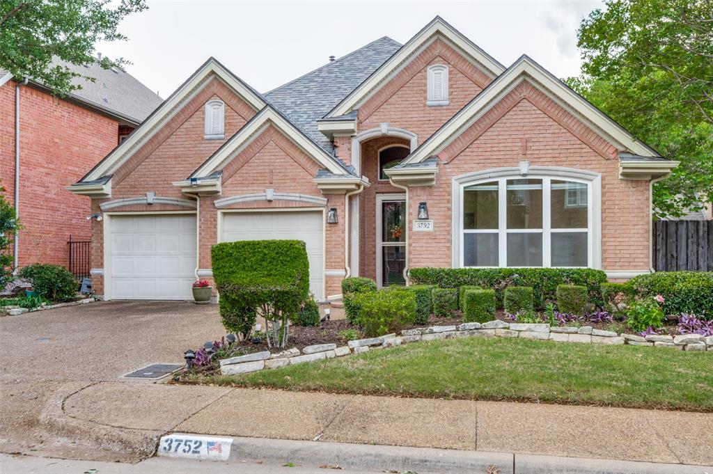 The property features a brick exterior with a grey shingle roof, an attached two-car garage, and a well-maintained front lawn with established landscaping