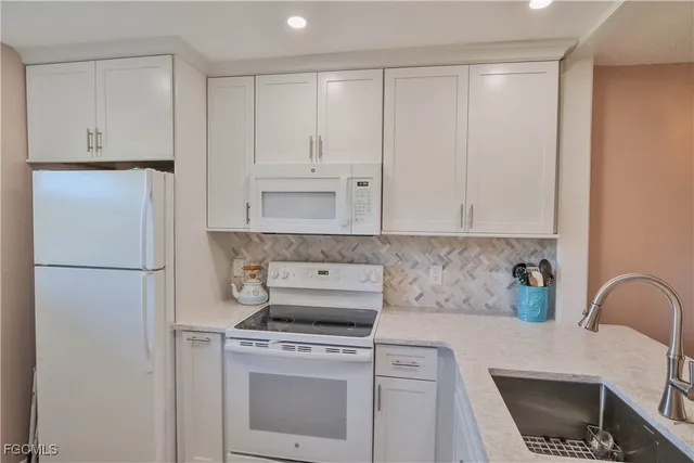 a kitchen with a refrigerator stove and white cabinets