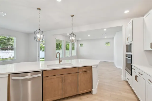 a view of a kitchen with kitchen island a stove a wooden floor and a large window