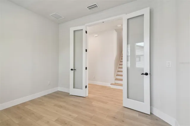 an empty room with wooden floor and windows