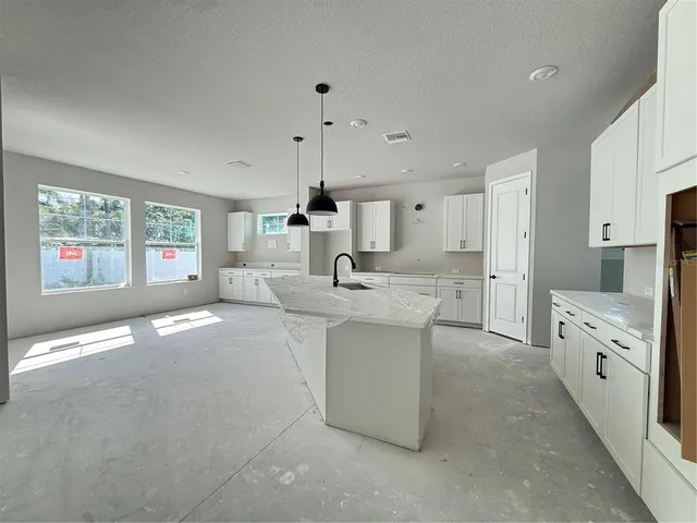a kitchen with white cabinets a sink a window and stainless steel appliances