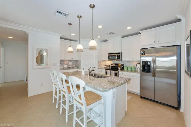 a kitchen with granite countertop a center island a refrigerator and a counter top space