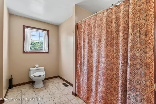 a bathroom with a toilet and a shower curtain