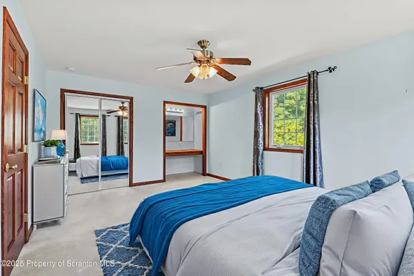 a view of a big room with windows and chandelier fan