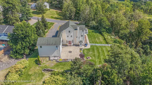 an aerial view of residential house with outdoor space and trees all around