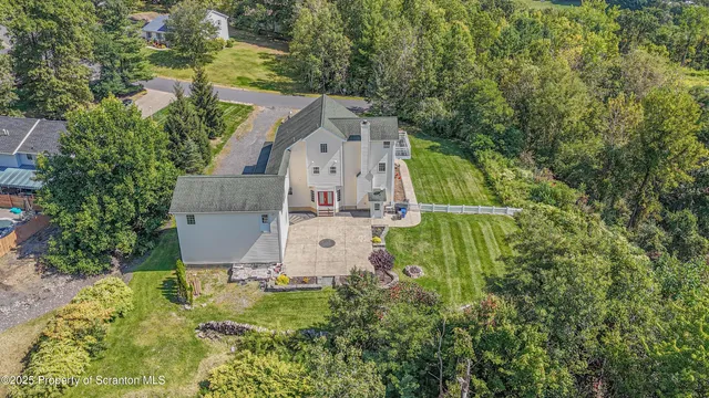 an aerial view of residential house with outdoor space and trees all around