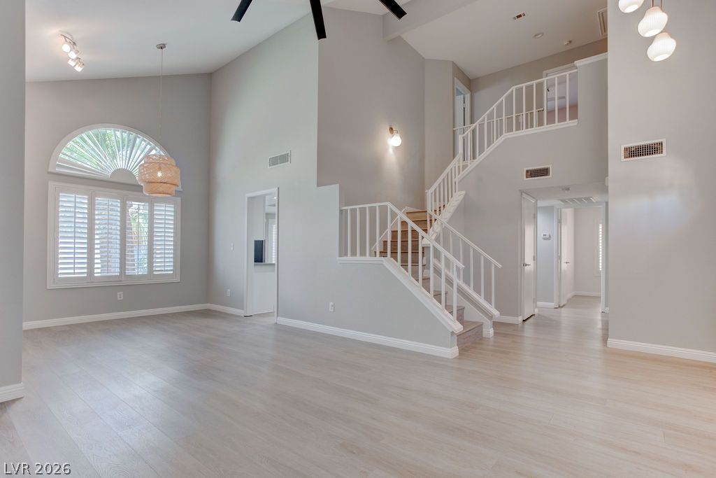 1416 Walstone Road North Las Vegas, NV 89031 - Photo 5 of 47 Natural light bathes this spacious entry, showcasing soaring ceilings and light wood-look flooring leading to an elegant staircase.