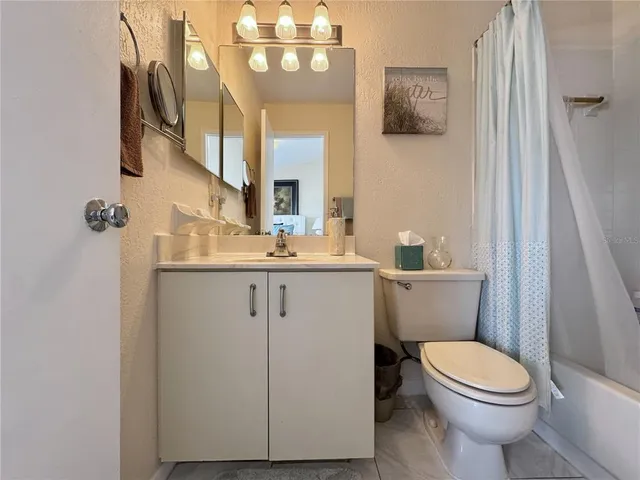 a bathroom with a granite countertop toilet sink and mirror