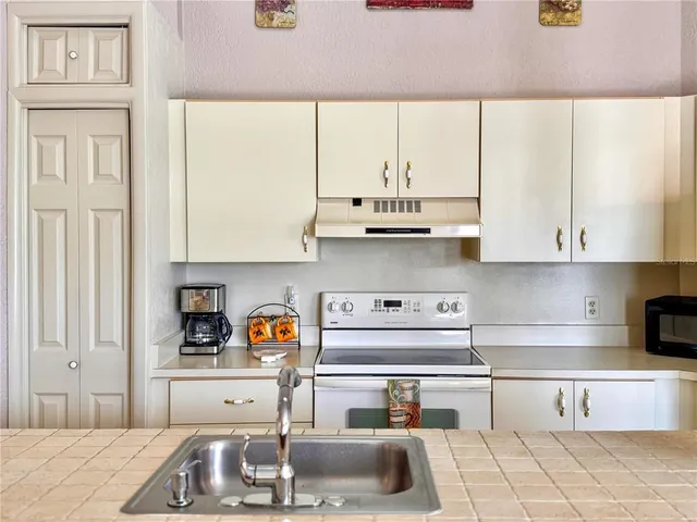 a kitchen with stainless steel appliances granite countertop a sink a stove and white cabinets