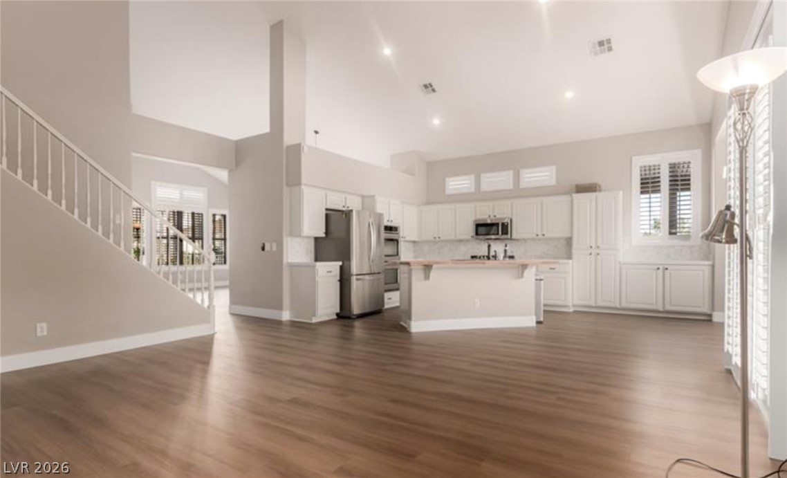 264 Pointe Ranier Avenue Henderson, NV 89012 - Photo 5 of 43 A grand living space with high ceilings flows into a kitchen featuring bright white cabinetry and an island.