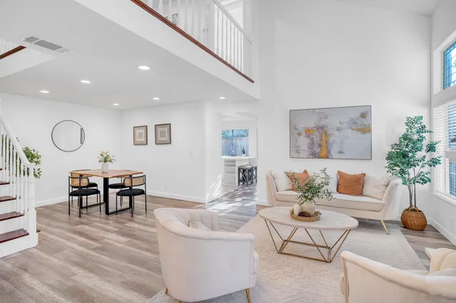 a living room with furniture and a dining table with wooden floor