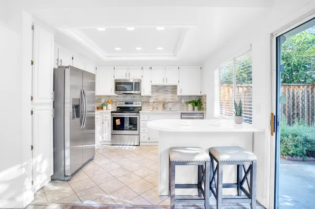 a kitchen with stainless steel appliances a refrigerator a stove a sink dishwasher and a refrigerator with wooden floor