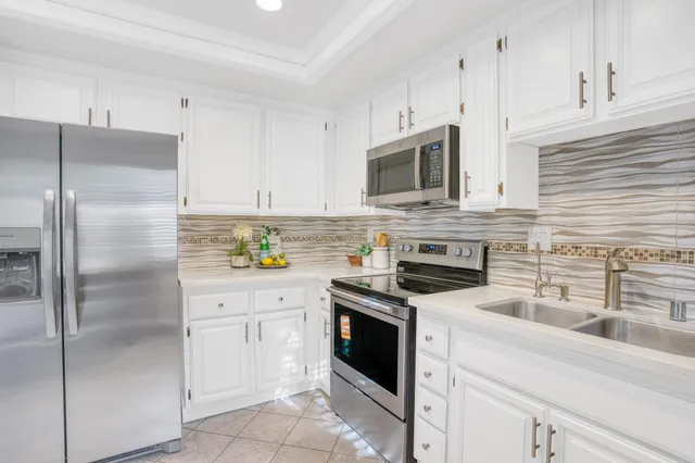 a kitchen with stainless steel appliances granite countertop a refrigerator a stove a sink and white cabinets