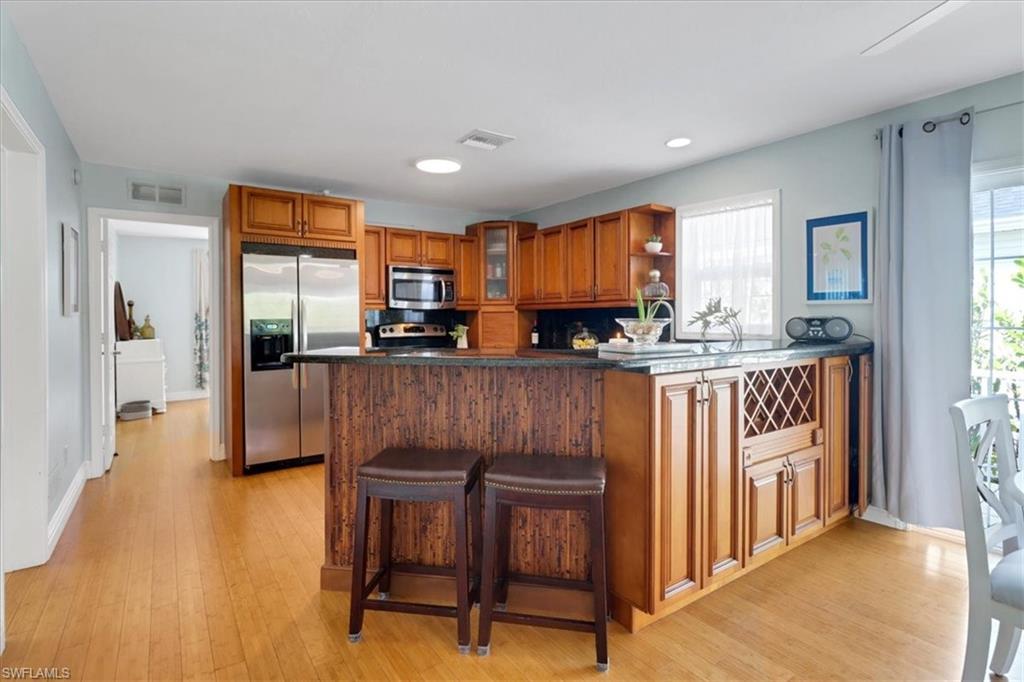 370 Leawood Circle Naples, FL 34104 - Photo 9 of 31 a kitchen with stainless steel appliances granite countertop a sink a stove a microwave a dining table and chairs