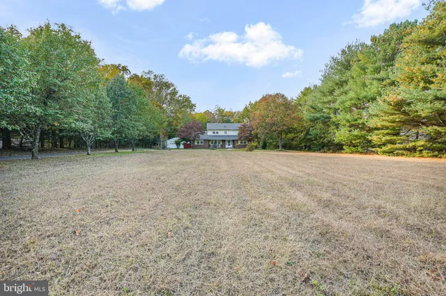 a view of an empty room with wooden floor fireplace and a window