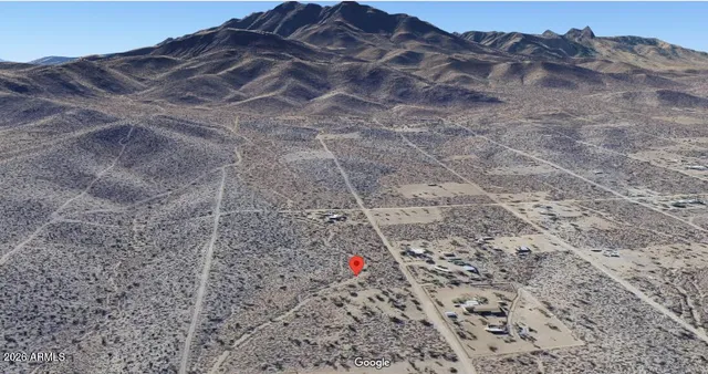 a view of a dry field with mountains in the background
