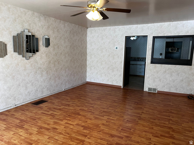 338 South 300 West Helper, UT 84526 - Photo 6 of 20 Empty room with wood finished floors, ceiling fan, and wallpapered walls