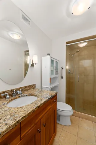 a bathroom with a granite countertop sink toilet and shower