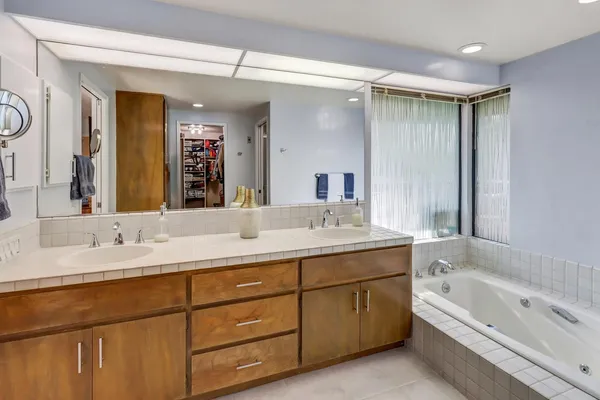 a bathroom with a tub a sink double vanity and mirror