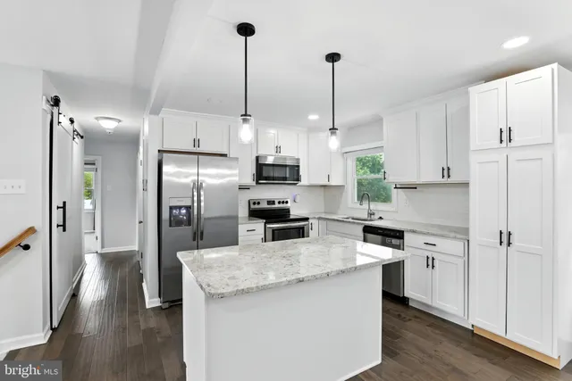 a kitchen with stainless steel appliances granite countertop a sink a refrigerator a stove and a wooden floors