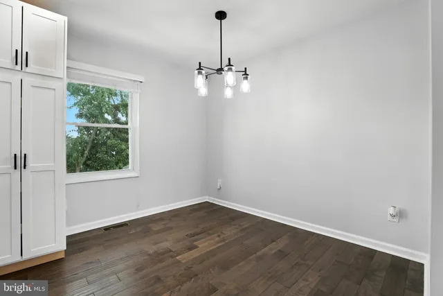 an empty room with wooden floor chandelier and windows