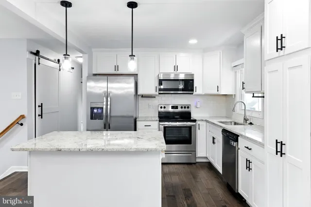 a kitchen with stainless steel appliances a sink stove refrigerator and cabinets