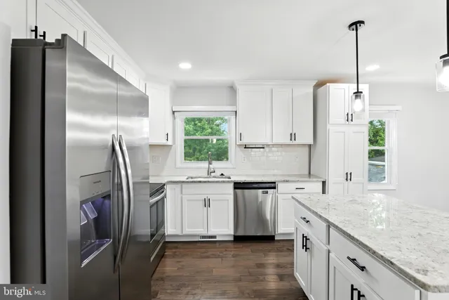 a kitchen with stainless steel appliances granite countertop a sink refrigerator and window