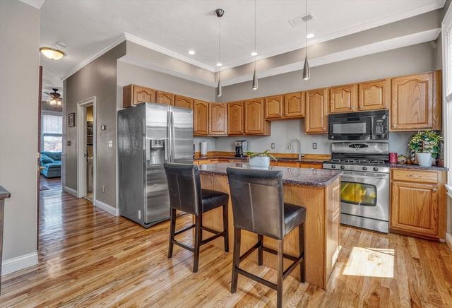 a kitchen with granite countertop a table chairs microwave and cabinets