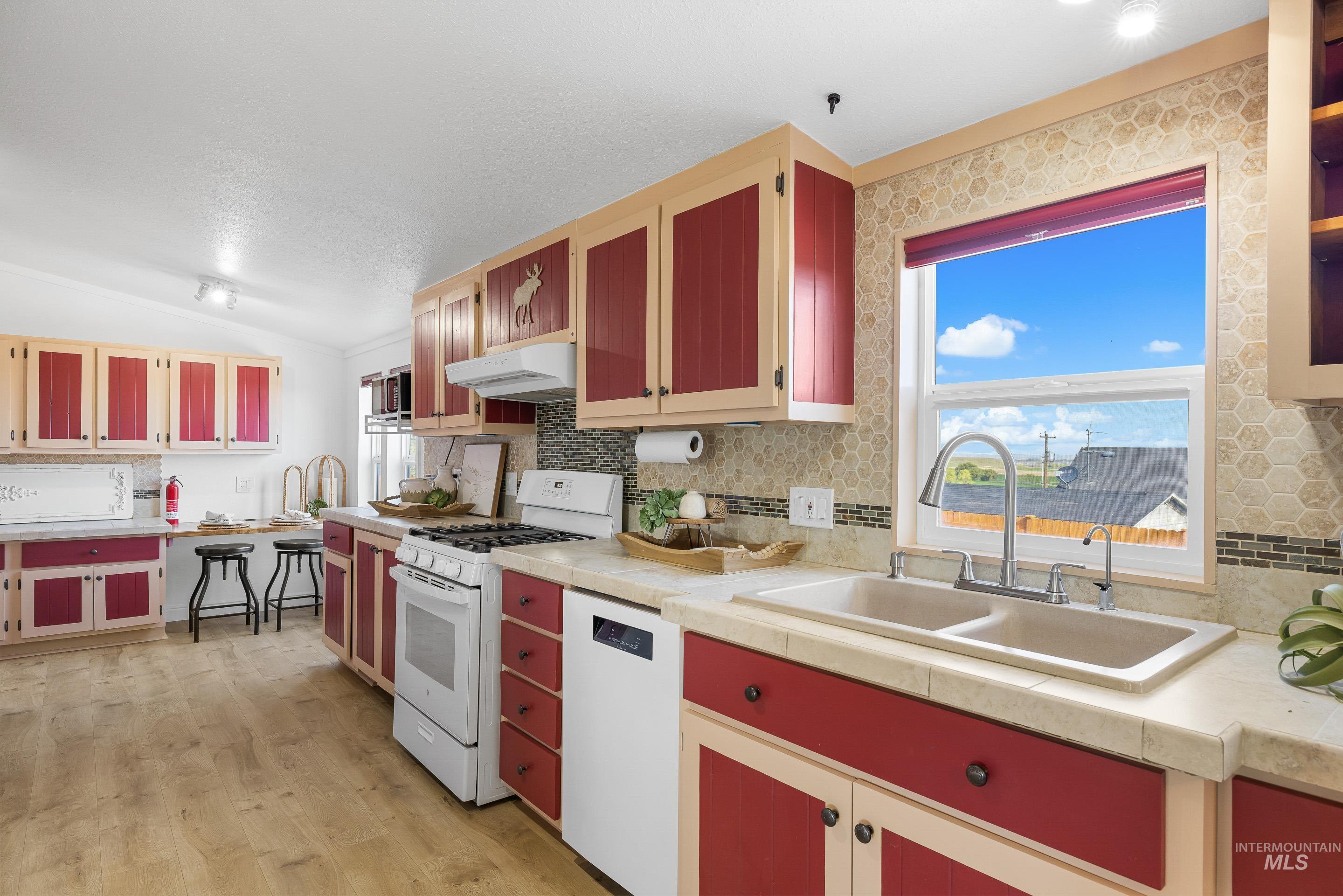 2427 Northside Road Homedale, ID 83628 - Photo 11 of 49 Two tone kitchen with white appliances, light countertops, two tone cabinetry, tasteful backsplash, and light wood finished floors