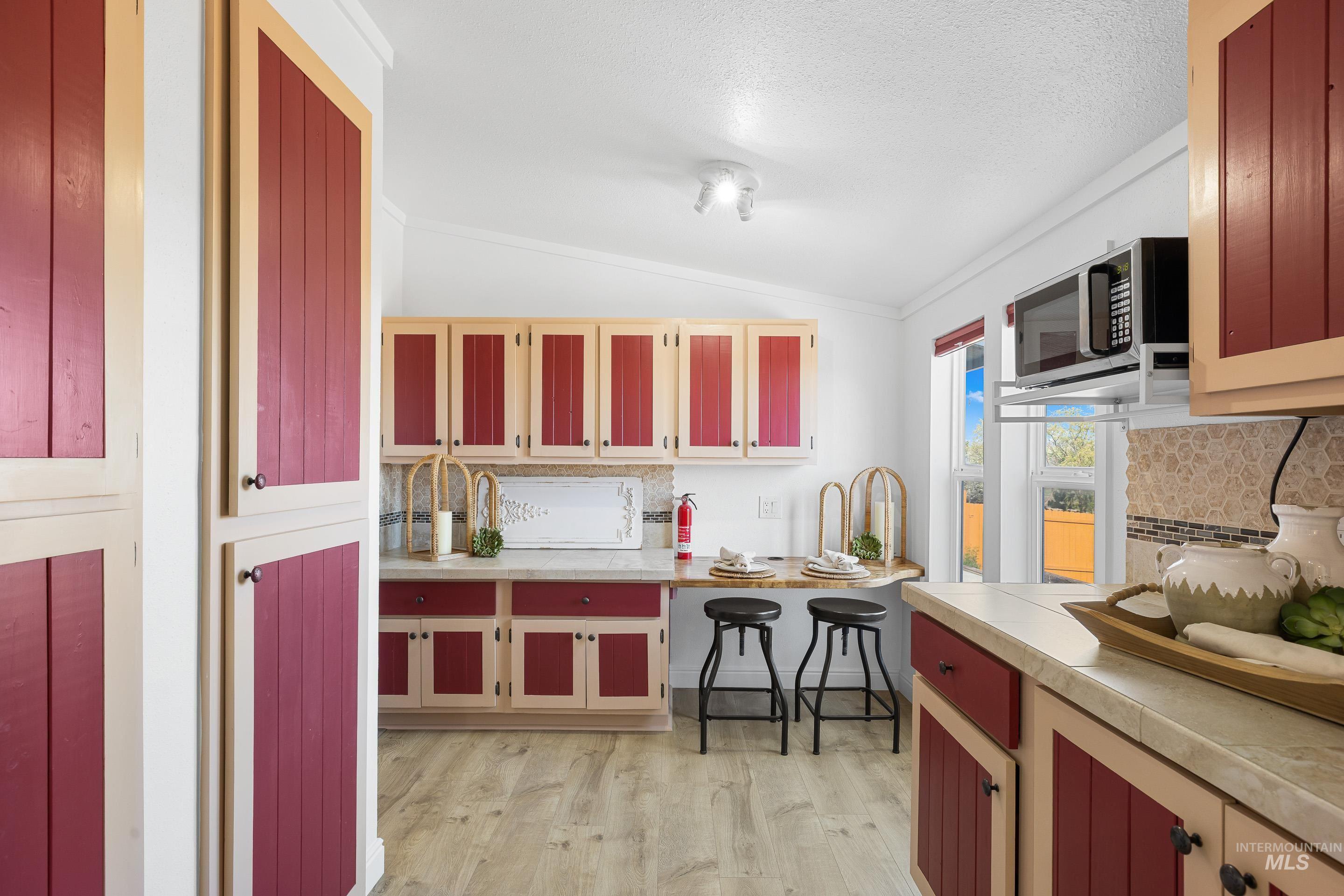 2427 Northside Road Homedale, ID 83628 - Photo 13 of 49 Kitchen featuring light countertops, decorative backsplash, stainless steel microwave, light wood-type flooring, and crown molding