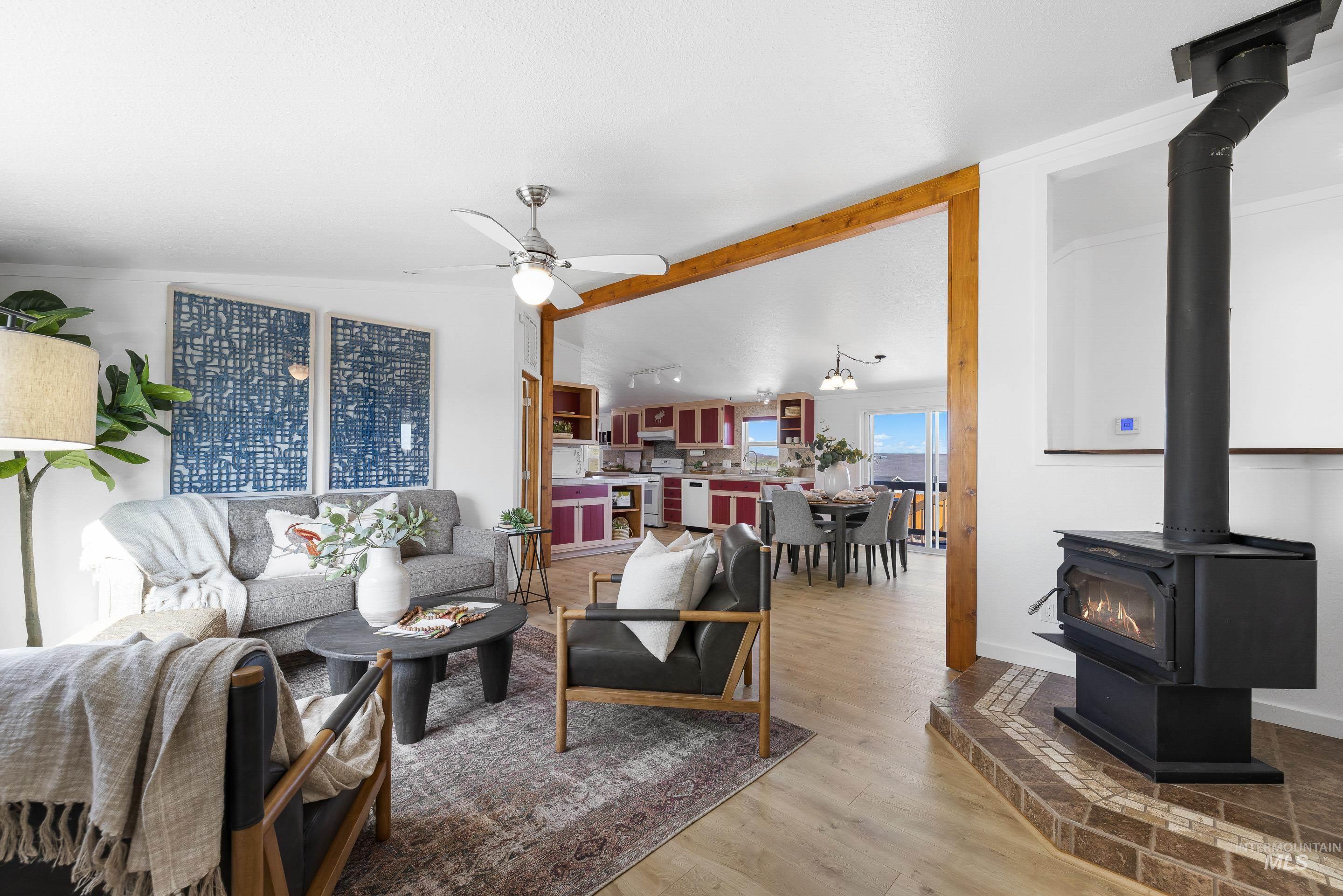2427 Northside Road Homedale, ID 83628 - Photo 6 of 49 Living area with lofted ceiling with beams, a wood stove, a ceiling fan, and light wood-type flooring